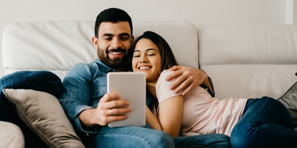 Couple on a couch, watching a tablet